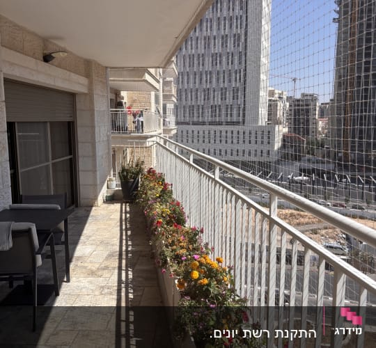 מרפסת עם רשת למניעת יונים וצמחי נוי